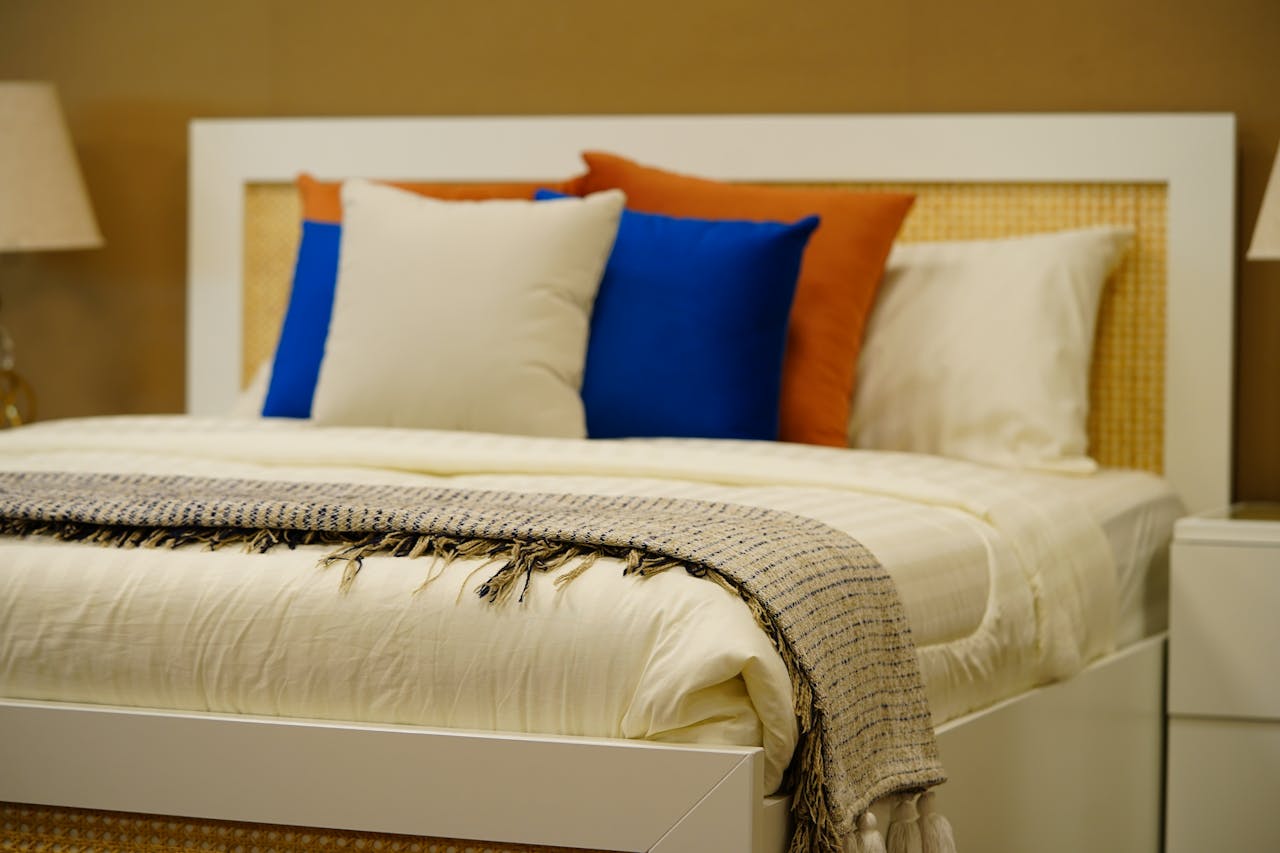 A stylish modern bedroom featuring vibrant pillows, soft textures, and warm ambiance in elegant decor.